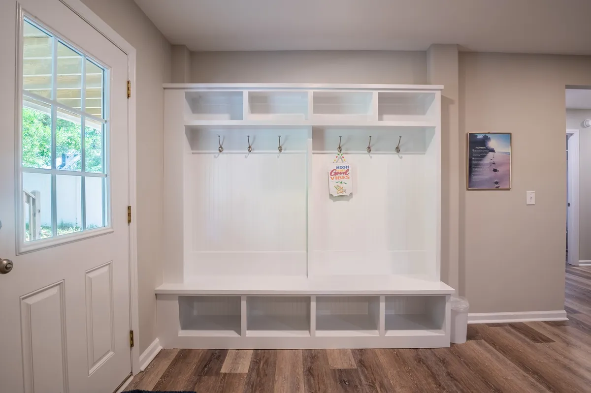A welcoming entryway featuring a wooden bench, hooks for jackets and bags, and a decorative sign. This space captures the transition between indoor comfort and outdoor adventure, offering a snapshot of daily comings and goings as guests return from exploring the coast.